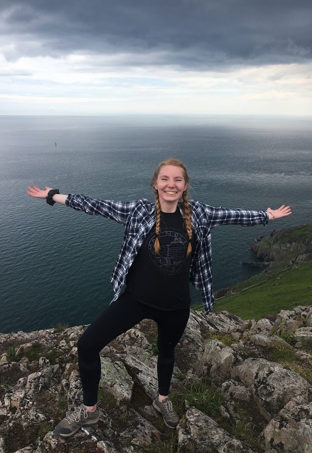Student standing on mountain with the ocean in the background