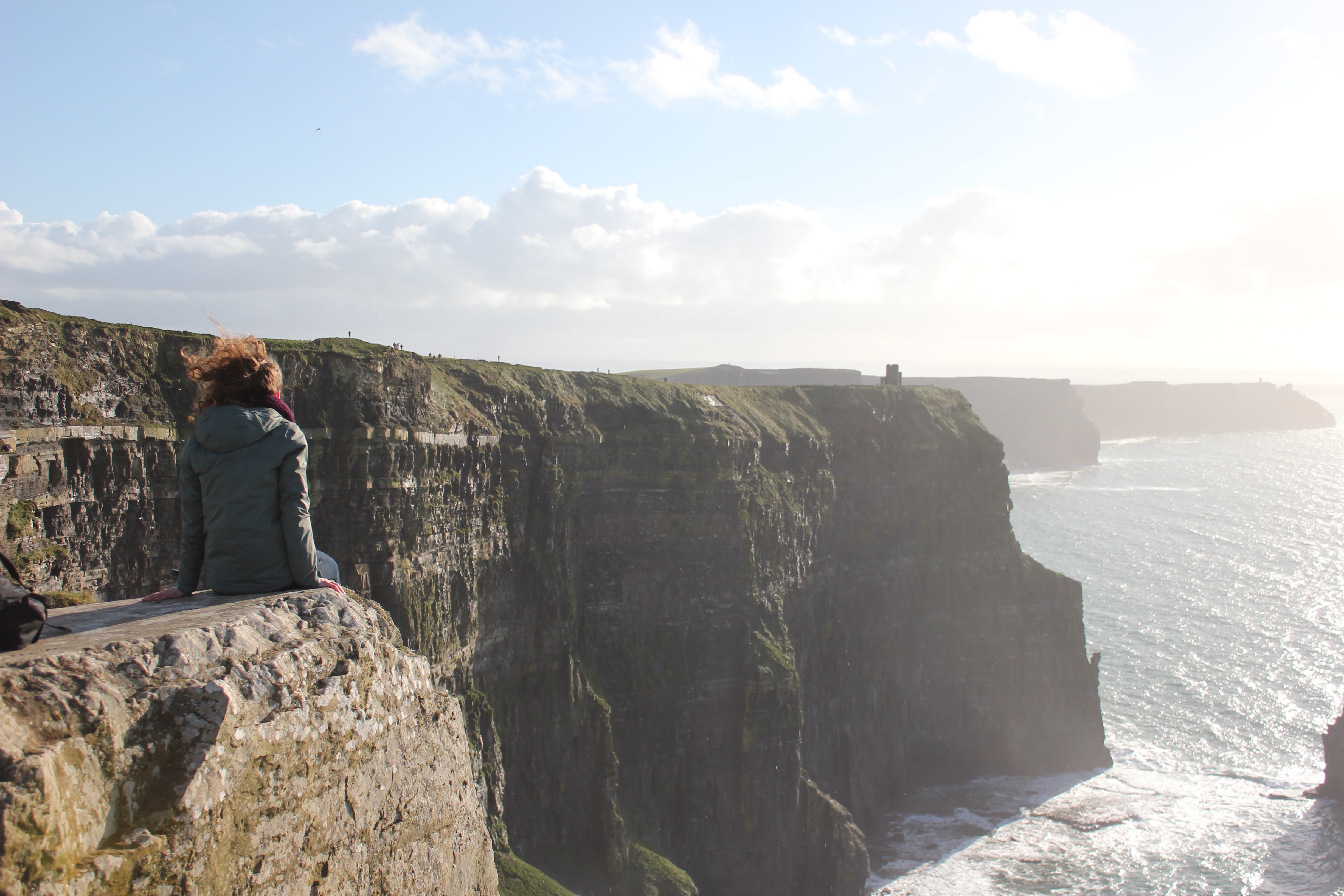 a student sitting on ocean cliff